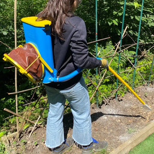 Person using a backpack sprayer in a garden setting