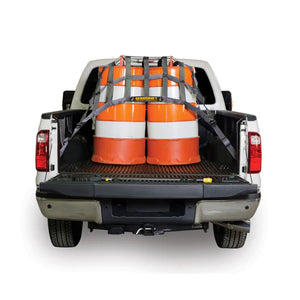 Truck bed with safety barrels secured using a Brakeline truck bed cover and straps on a white background.