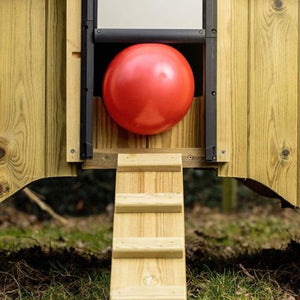 Red ball on a wooden chicken coup ramp against a wooden wall