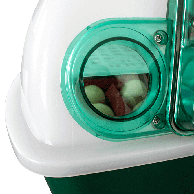 Close-up of a green and white incubator with a transparent cover, showing internal components.