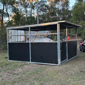 Large metal and black panel structure outdoors with a horse in it and trees in the background