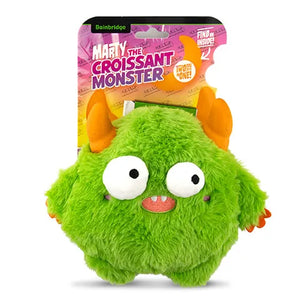 Green plush toy with orange horns and white eyes, featuring 'Marty the Croissant Monster' packaging.