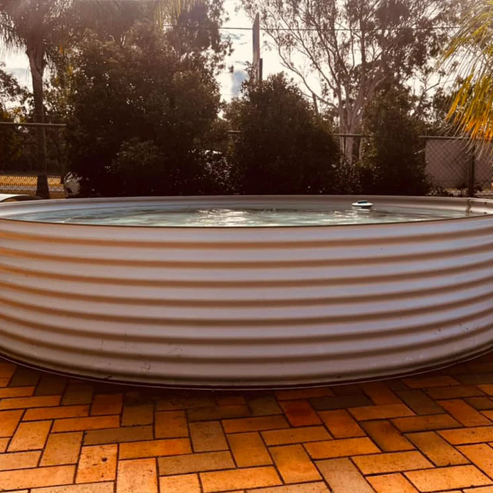 Large metal plunge pool on a brick patio with trees in the background