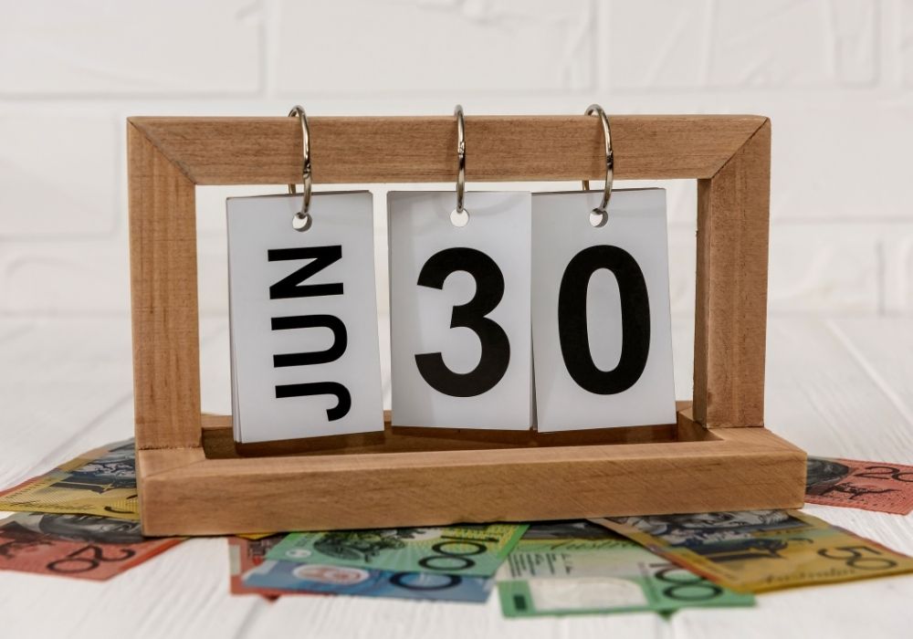 A calendar sign on top of some Australian money that's there to let you know it's June 30thj