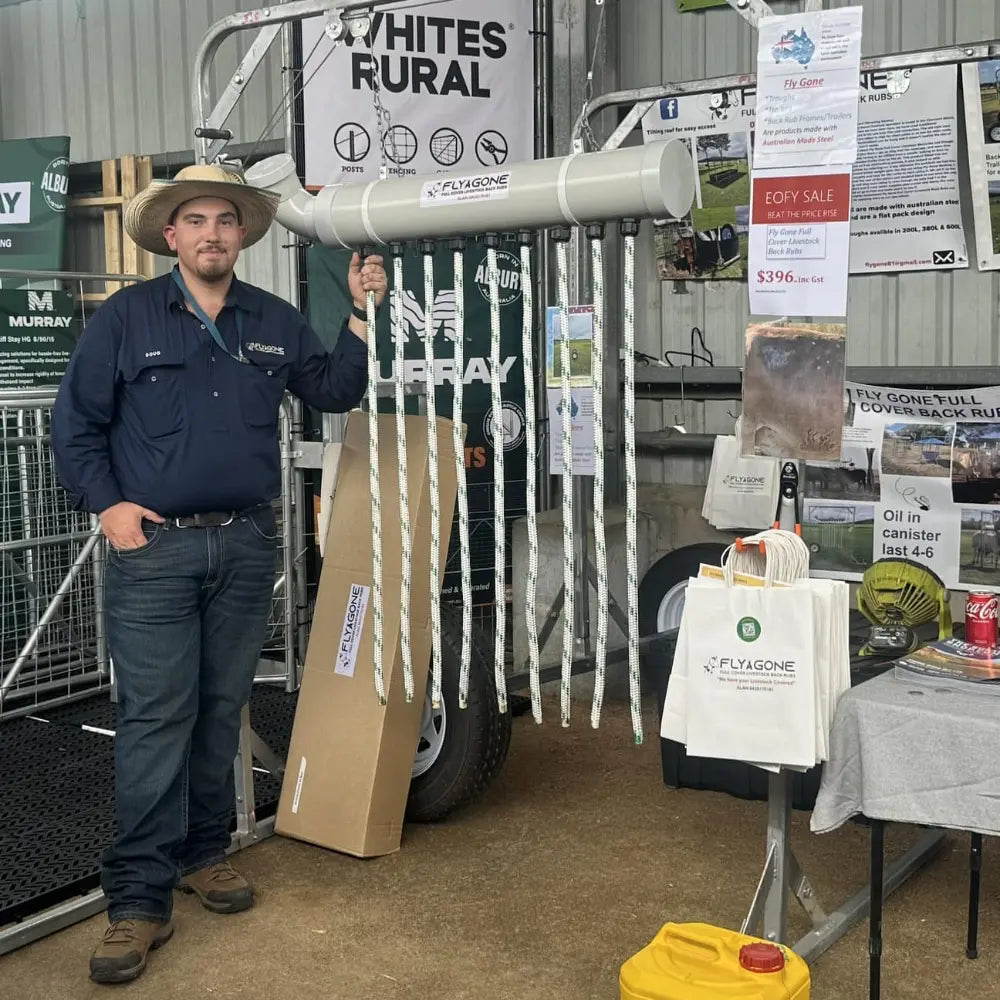 Man holding a fly gone cattle pest control device with multiple wicks in a display at a farm equipment show event.