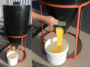 Black mini silo being used to transfer yellow grain into a white bucket.