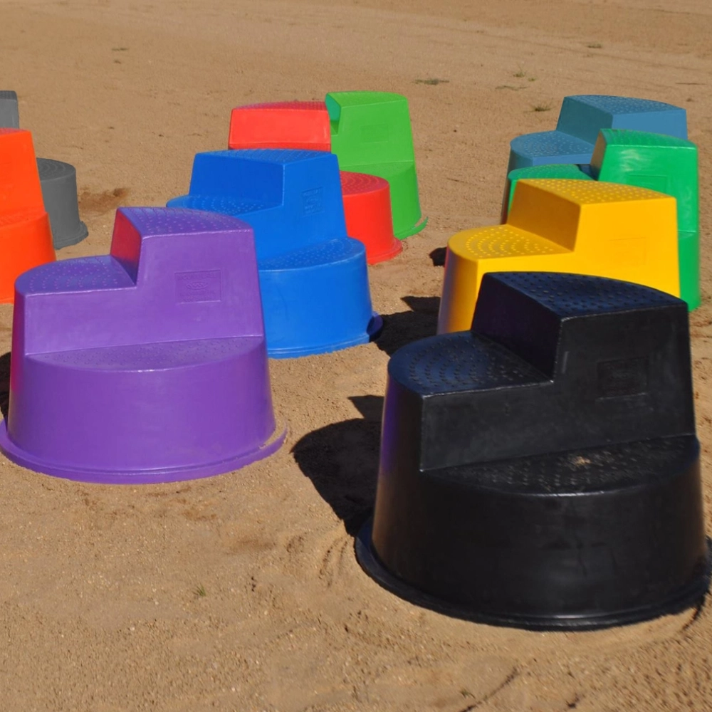 Colorful plastic horse mounting steps and platforms on a sandy surface